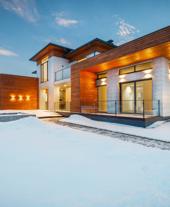 Modern house covered in snow, showcasing a serene winter scene.